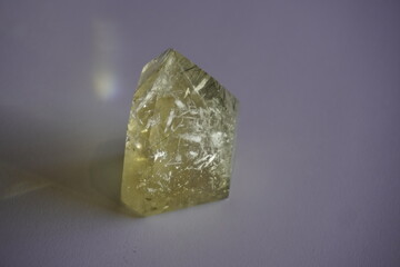 Rutilated quartz crystal in golden tones with reflection on white background and brilliance