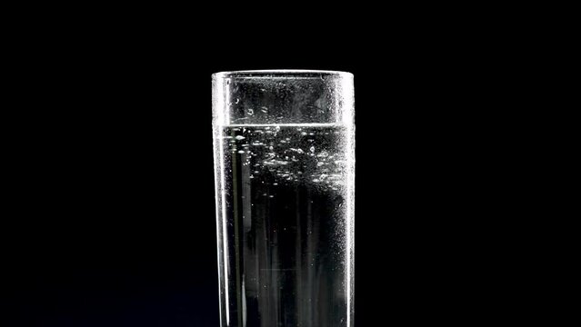 Drinking water in a rotating glass on a black background. Fresh drinking water. Fresh drink concept. Soft Focus, Selective Focus