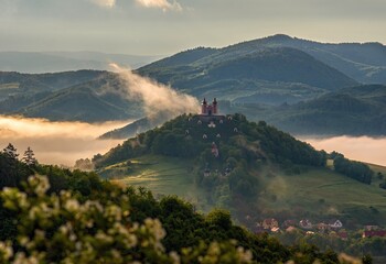 Church on the hill in wonderful warm sunset light. Summer morning at sunrise with fog and historic...
