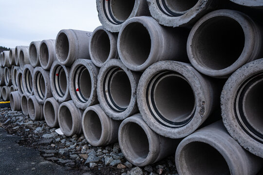 Large pile of concrete drain pipes at a construction site.