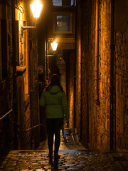 Following female tourist as she explores dark narrow alley on a rainy evening