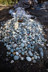 Large pile of round river rocks ready for spring gardening, outdoor public park on a sunny day

