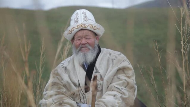 An old man in the mountains tunes and plays the Kyrgyz musical instrument komuz