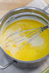 Melted butter with milk in a saucepan. The process of preparing a dish using a whisk
