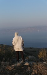 A Jewish man wraps himself in a tallit in prayer in nature