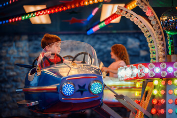 Twilight sets the stage for a young boy's delightful adventure in a blue starry bumper car amidst a...