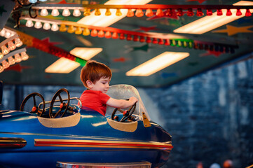 Twilight sets the stage for a young boy's delightful adventure in a blue starry bumper car amidst a kaleidoscope of fair lights