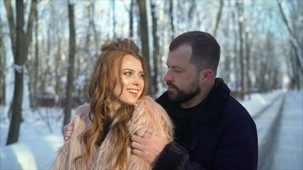 Girl and boy bask in the winter in the park. The guy and the girl are resting in the winter forest. Young couple walking in a winter park.