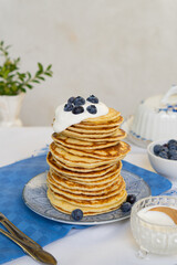 Tall stack of pancakes decorated with fresh blueberries