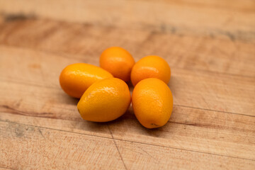 fresh Kumquats on wooden cutting board.