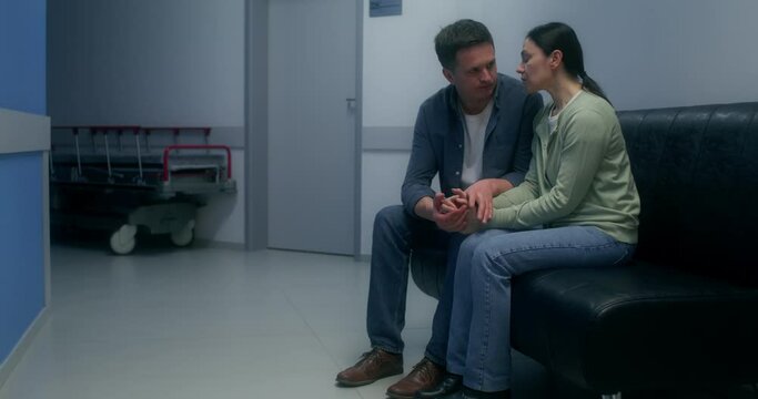 Concerned patient's relatives are waiting sitting on the couch in the hospital corridor
