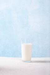 Glass jug with milk and a glass of milk on a light blue background