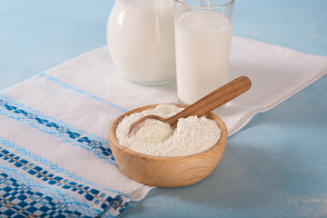 Powdered milk on a blue background and whole milk in a jug and glass