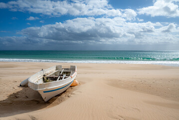 Fototapeta na wymiar Abandoned Boat on a Secluded Sandy Beach with Cloudy Sky