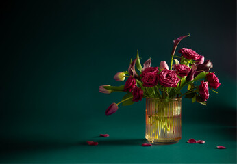 beautiful flowers in glass vase on green background