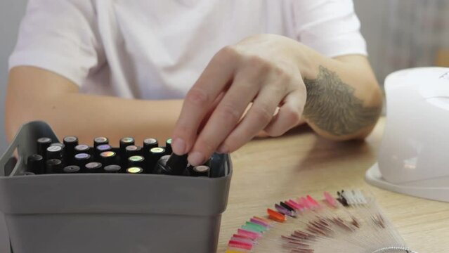The girl, seated at the table, carefully selects a nail polish color, embodying self-reliance and confidence. This moment symbolizes the concept of self-care and creative expression through manicure.