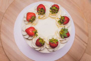 Sweet cake with strawberries on plate on wooden background.