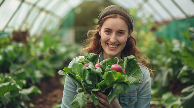 Young woman holding organic pink radish in a greenhouse