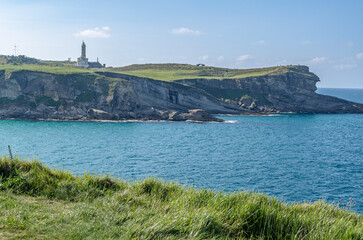 Rocky coast with the Cabo Mayor lighthouse in the background, Santander, Spain