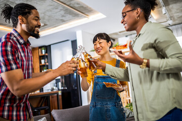 Multiethnic group of friends drinking beer and eating pizza at home.