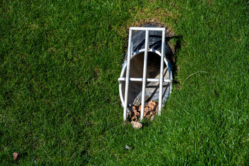 New storm water management culvert pipe and protective grate in a grassy bank
