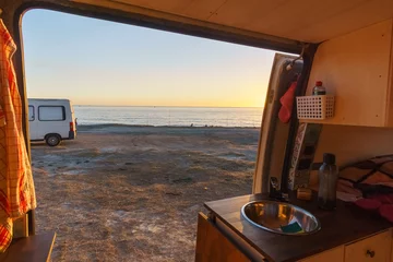 Zelfklevend Fotobehang View out of a self built camper van at a beach of the mediterranean sea with colorful sunset over the water surface, Andalusia, Spain © Sebastian