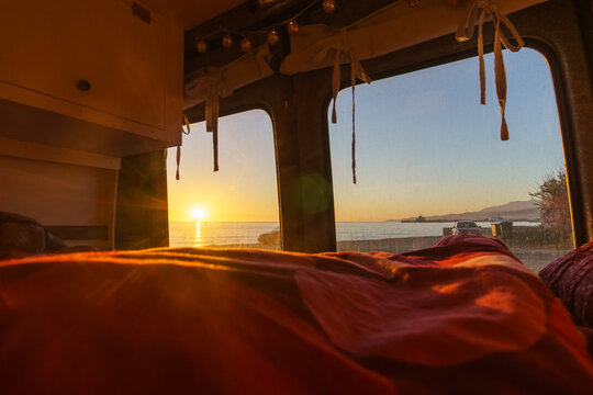 View out of a self built camper van at a beach of the mediterranean sea with colorful sunset over the water surface, Andalusia, Spain - Powered by Adobe
