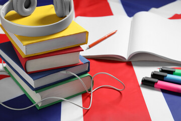 Learning foreign language. Different books, headphones and stationery on flag of United Kingdom,...