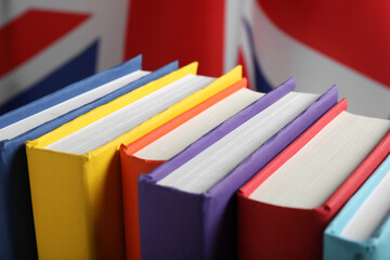 Learning foreign language. Different books near flag of United Kingdom, closeup