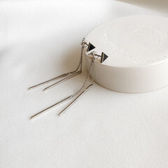 Stylish silver stud earrings with chains on plaster mold.