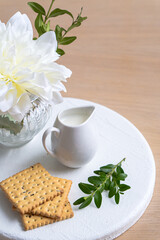 Cream with a small milk jug next to cookies on a white tray