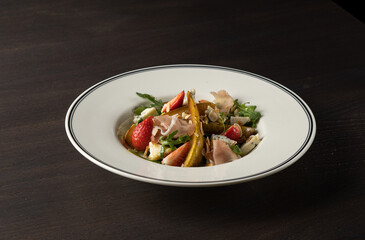 Salad with cheese, pear, strawberries and balsamic sauce. Close-up