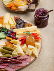 Cheese plate with many different snacks. Fruits, berries, crackers, honey, jam lie on the board.