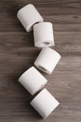 Soft toilet paper rolls on wooden table, flat lay