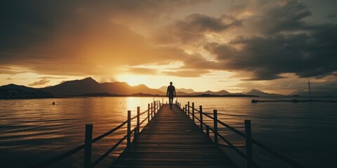 Obraz premium A man standing on a pier during a beautiful sunset. Perfect for travel and inspirational concepts