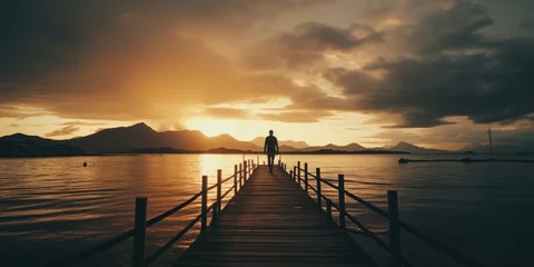 Fototapeten A man standing on a pier during a beautiful sunset. Perfect for travel and inspirational concepts © Fotograf