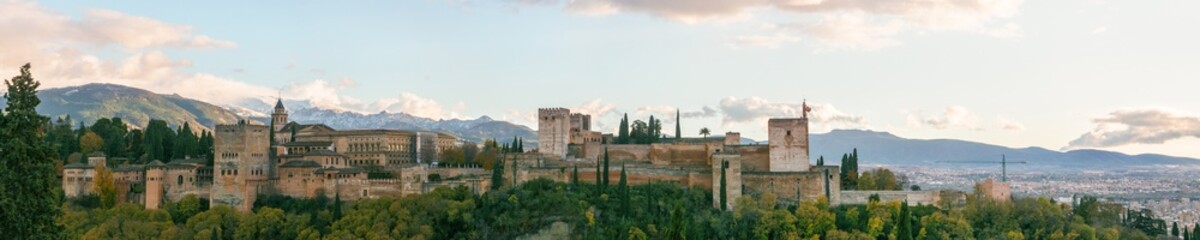 Panorama of fortress of Alhambra on a hill top seen from the quarter Albaicin with mountains of Sierra Nevada in background, Granada, Andalusia, Spain - obrazy, fototapety, plakaty