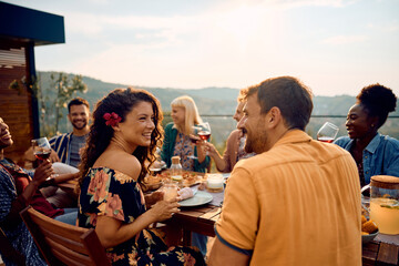 Happy couple talking while having lunch with friends at dining table on patio.