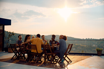 Multiracial group of friends having lunch at dining table on patio.