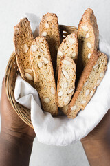 overhead view of almond biscotti in a small basket, almond cantucci cookies in a napkin lined basket, flatlay of biscotti cookies or twice baked cookies	