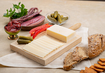 Cheese on a wooden board next to fruit on a beige background