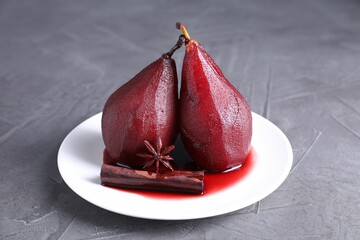 Tasty red wine poached pears and spices on grey table, closeup