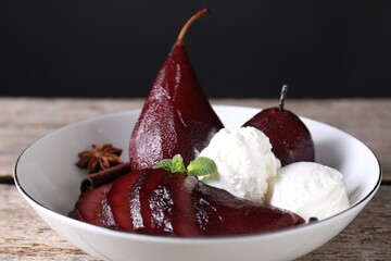 Tasty red wine poached pears and ice cream in bowl on wooden table, closeup