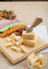 Cheese on a board with sun-dried tomatoes, cucumbers, crackers