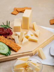 Cheese on a board with sun-dried tomatoes, cucumbers, crackers