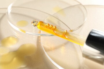 Pipette with moisturizing serum on beige background, closeup