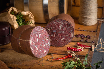Large thick rustic sausage on the table among spices and seasonings