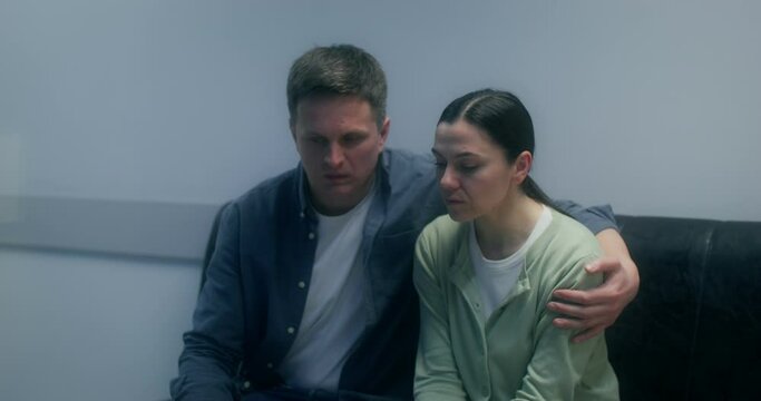 Concerned patient's relatives are waiting sitting on the couch in the hospital corridor