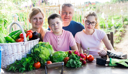 Friendly family discusses the harvest of vegetables at the table of the village house