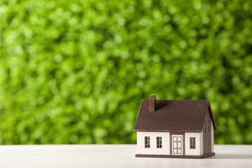 House figure on white table against decorative green grass. Concept of buying real estate
